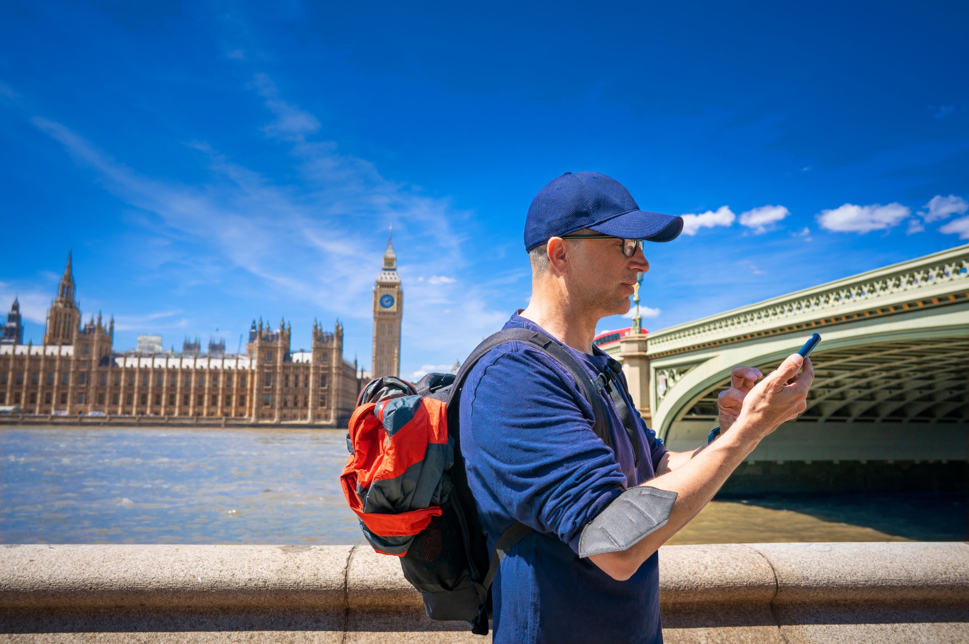 London tourist middle age man using smartphone at Big Ben Westminster bridge UK